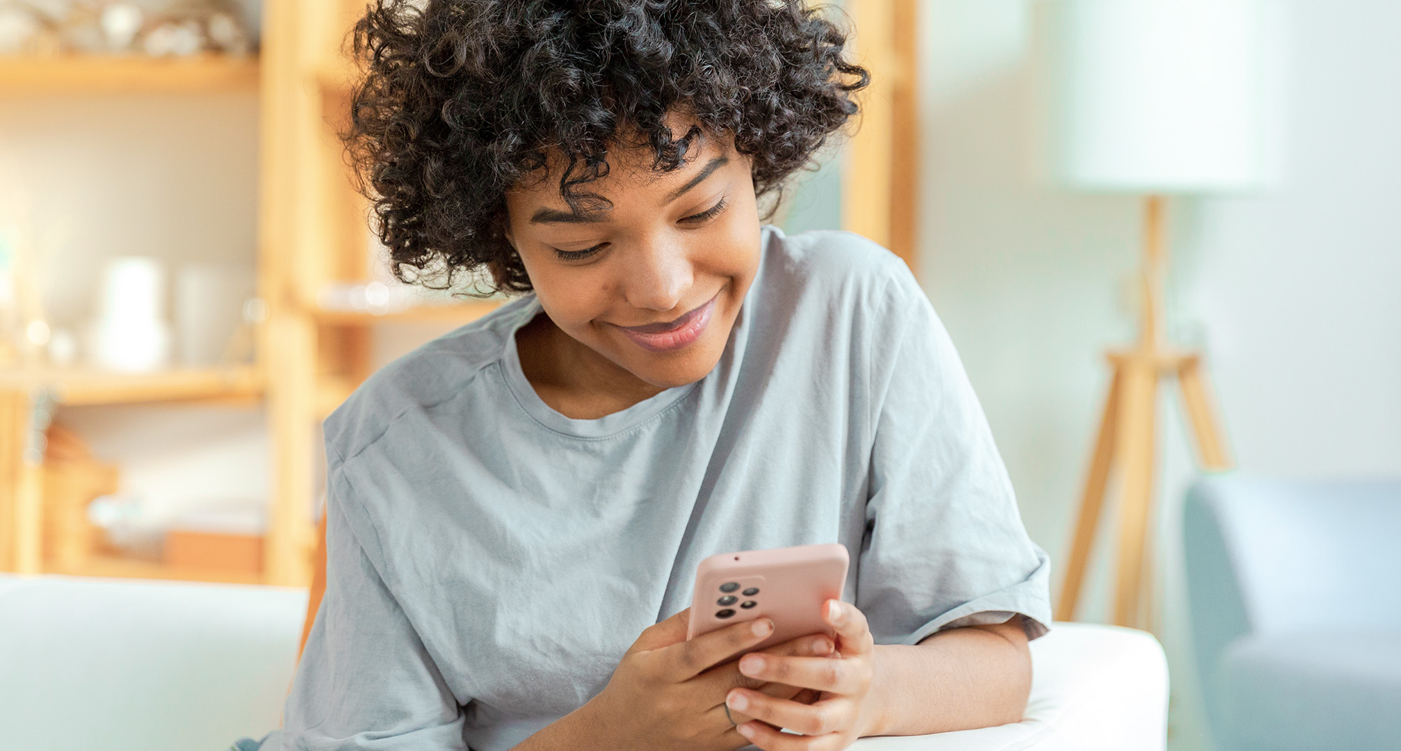 primer plano de una persona sonriendo y mirando el teléfono móvil