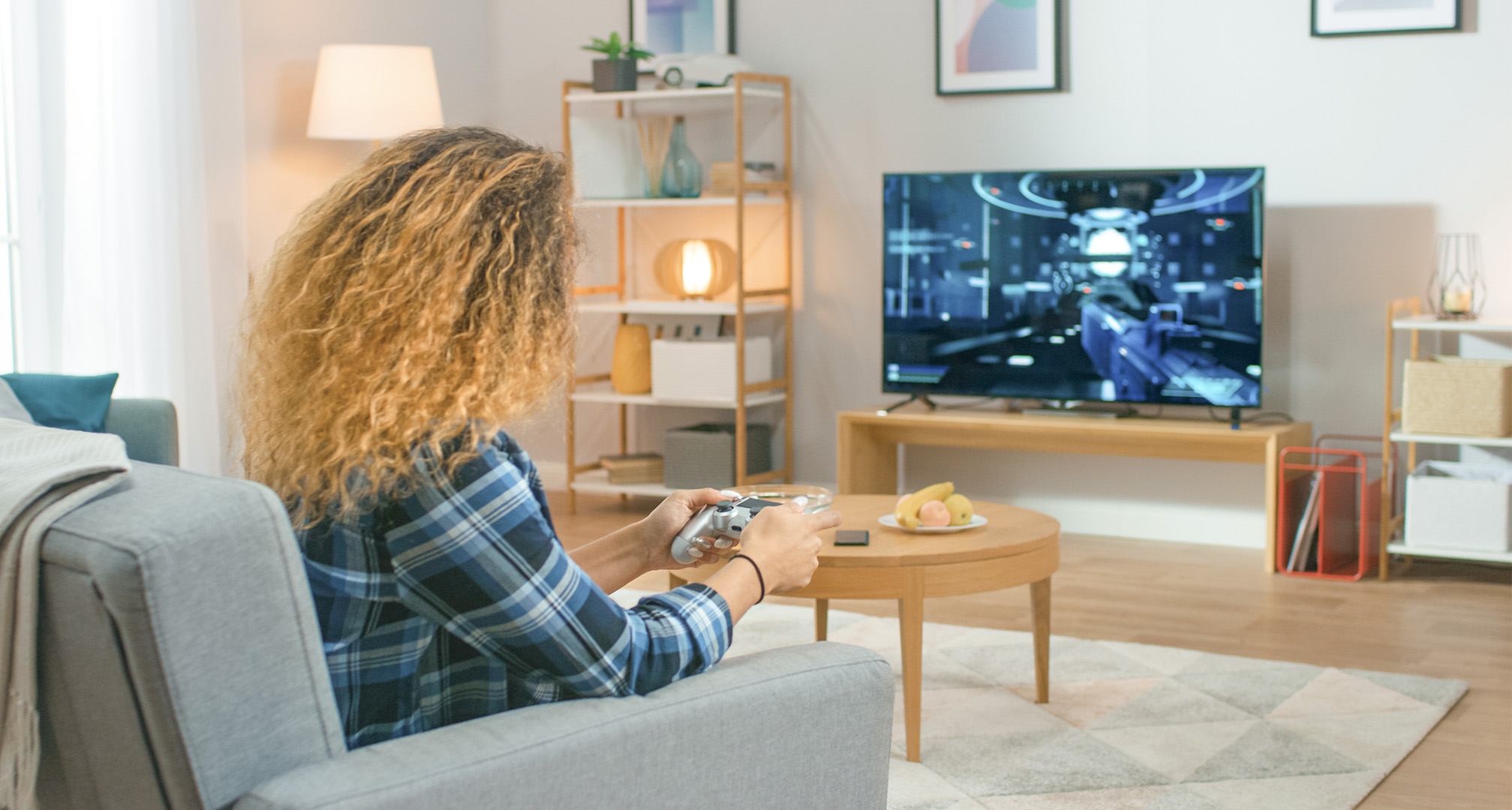 persona con pelo largo y rizado en el salón jugando a videojuegos en un televisor