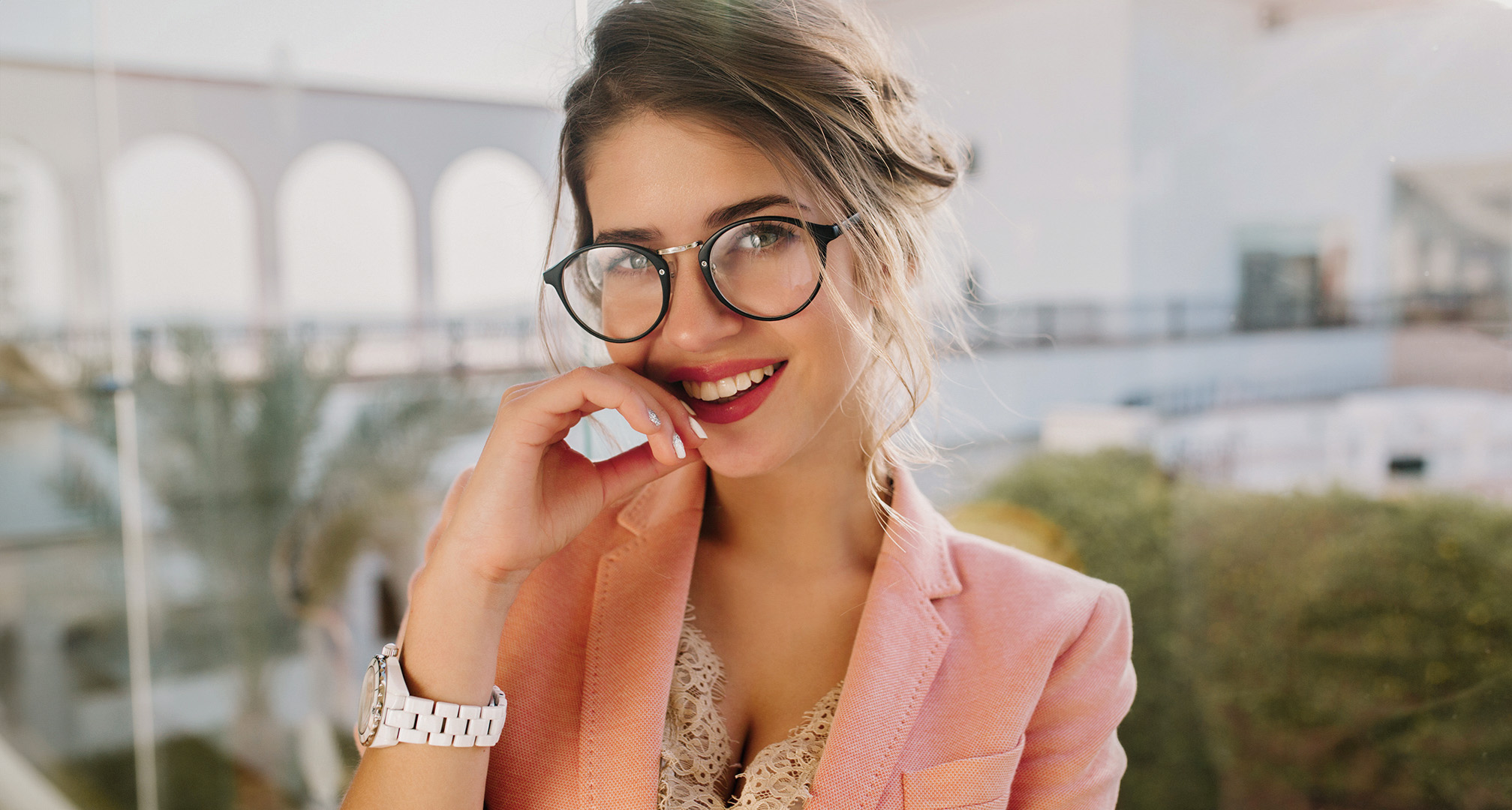 Persona con pintalabios rojo, gafas de montura negra y chaqueta blazer rosa