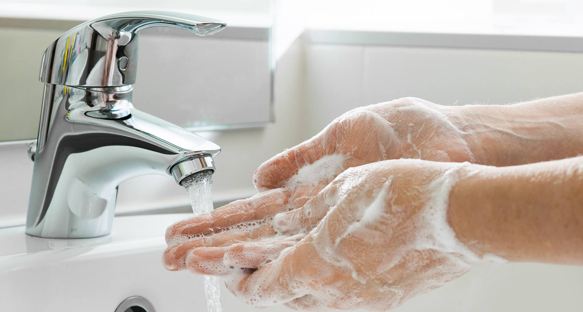 lavarse las manos enjabonadas bajo el grifo del fregadero