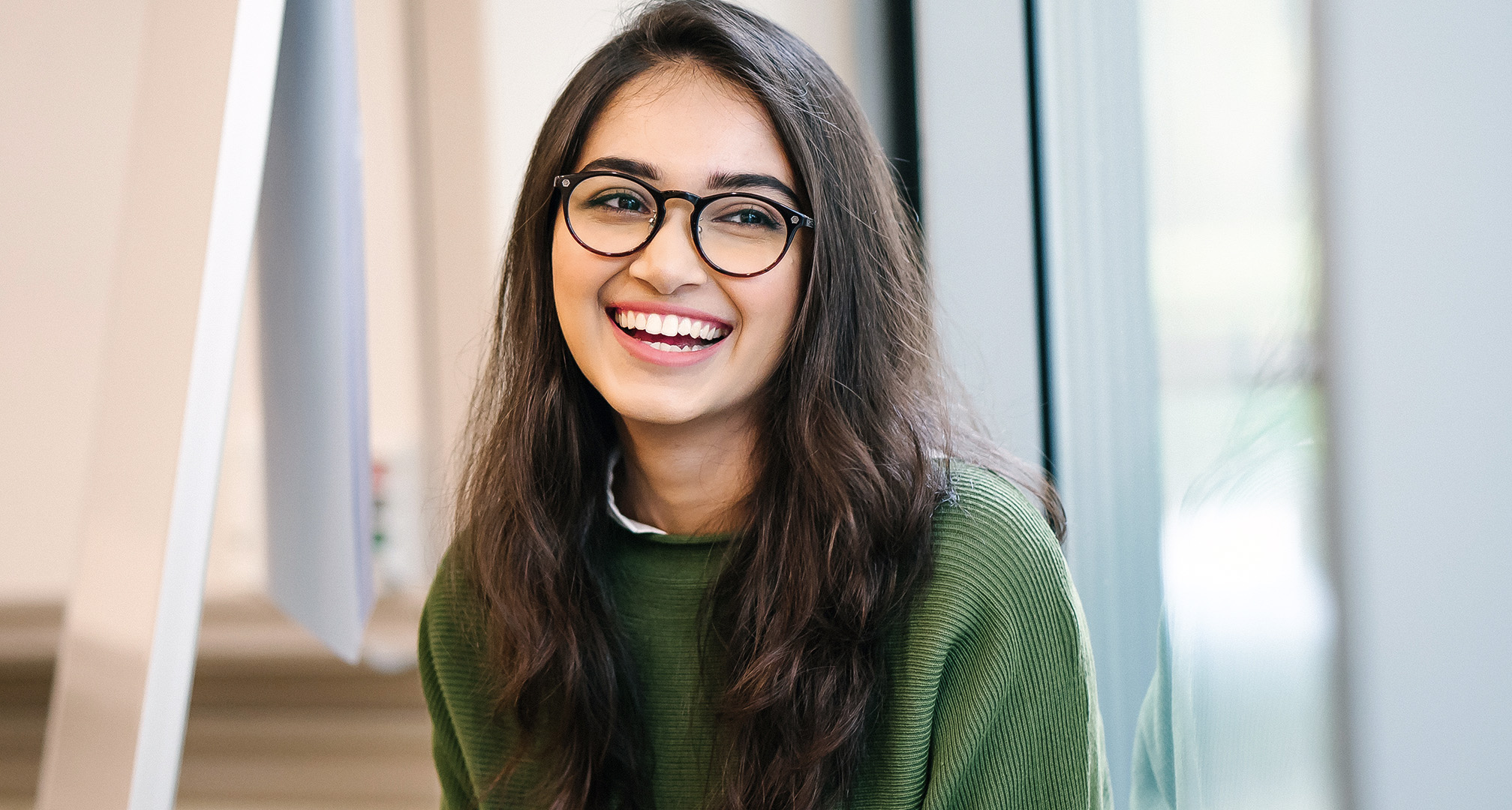 foto de una persona sonriente con pelo largo y gafas de montura negra