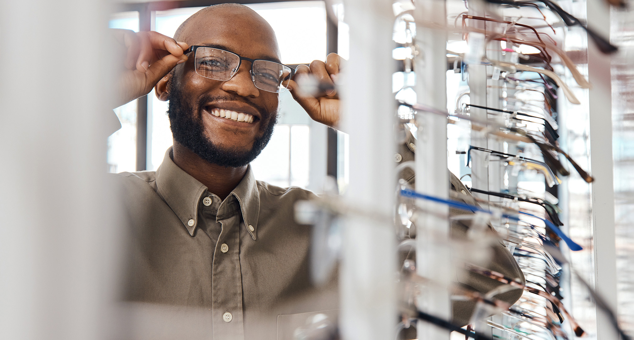 foto de una persona sonriente probándose unas gafas en la óptica