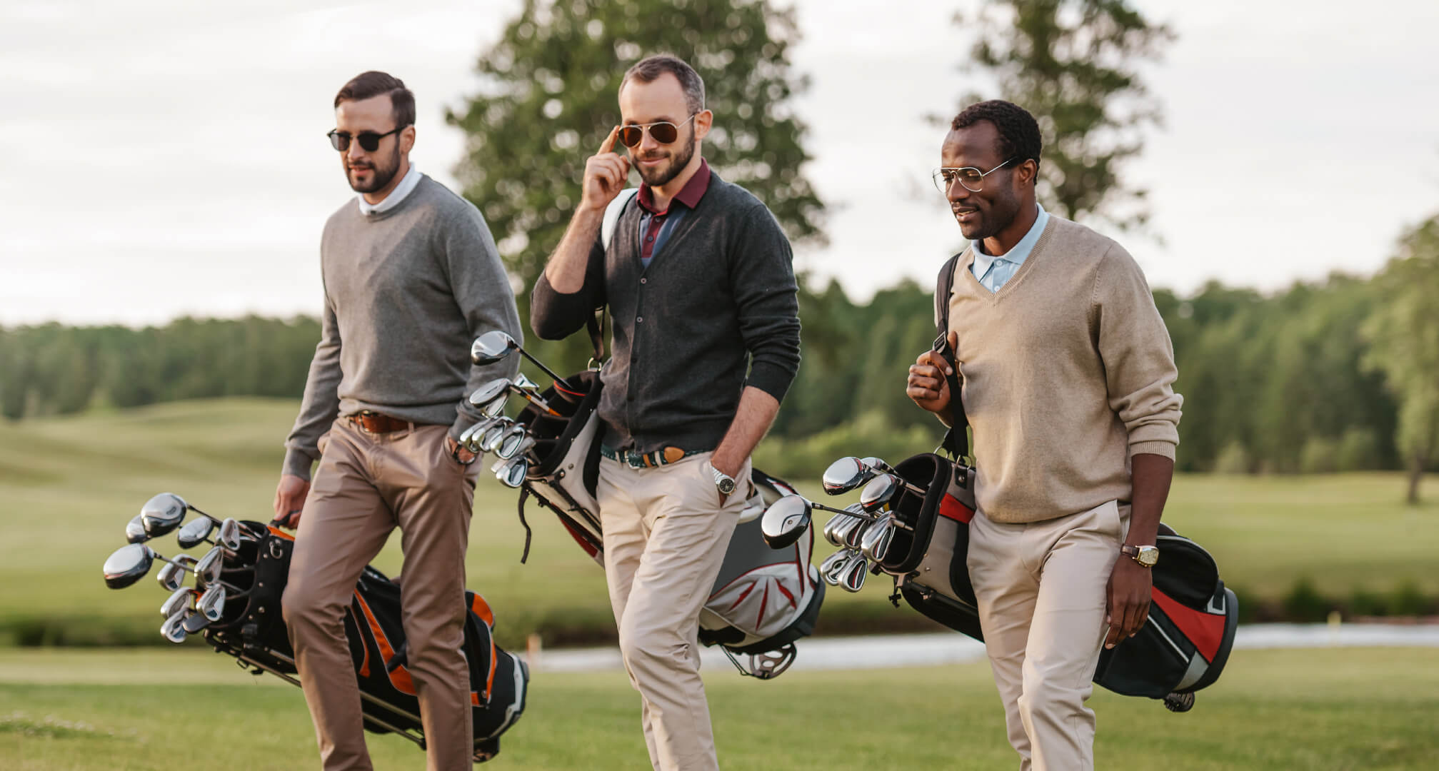 tres personas jugando al golf con gafas de sol y bolsas de golf